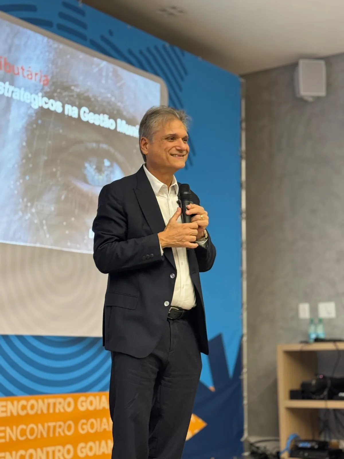 Edgar Madruga sorrindo com microfone durante uma apresentação